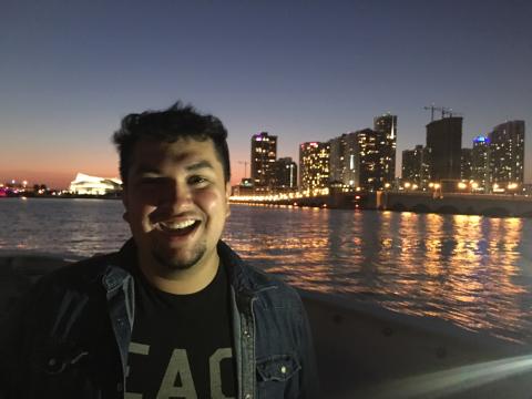 Photo of Junior Avalos next to a river and city skyline.