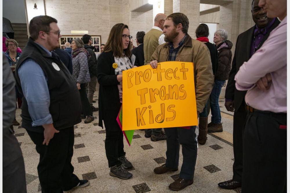 Courtney Cochran, one of the rally organizers, handed Duluth City Council President Noah Hobbs a sign to hold during the rally.