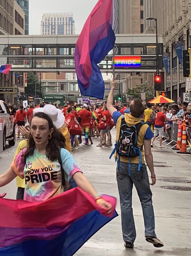 In front of marchers representing Target co., two people present their bisexual pride flags in the midst of the parade.