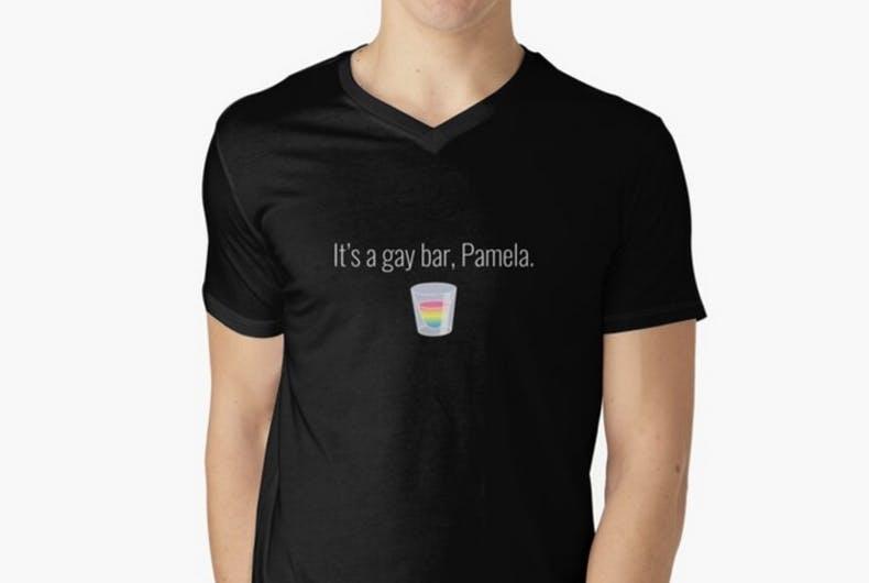 Photo of a black t-shirt with the text "It's a gay bar, Pamela." and a shot glass filled with rainbow-colored liquid.